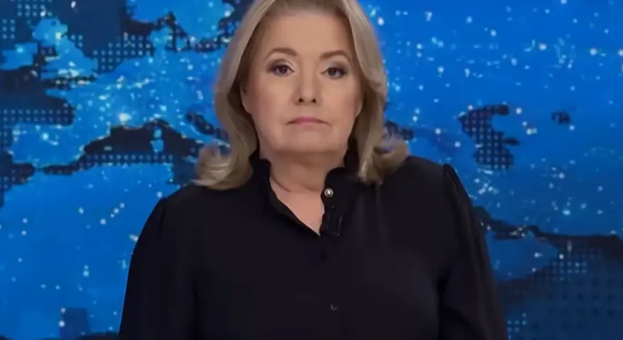 Kobieta w czarnej bluzce na tle mapy świata. Jej poważna mina sugeruje, że omawia ważne wiadomości, które wpływają na oglądalność.