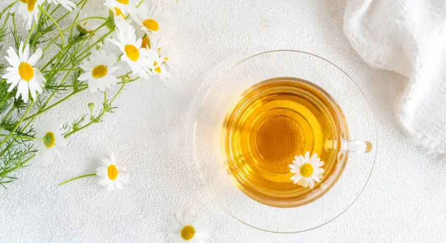 Un mazzolino di margherite e una tazza di tisana dorata. Nonostante la sua apparenza innocua, la camomilla fa male al cuore se consumata in eccesso.