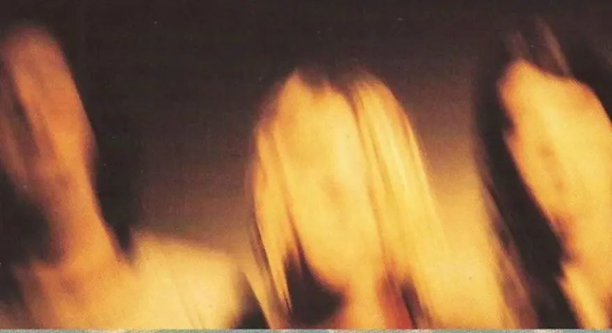 Rozmyte postacie, jakby w ruchu, na tle sugerującym okładkę albumu "Smells Like Teen Spirit" Nirvany.