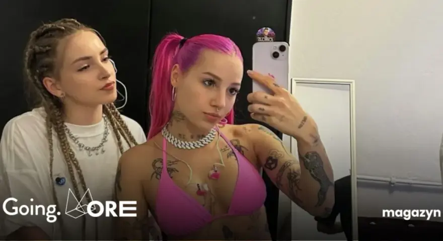 Dwie dziewczyny, jedna z różowymi włosami, druga z warkoczami, pozują do selfie. Jedna z nich, w różowym bikini, ma widoczne tatuaże. W tle logo "Going. MORE".