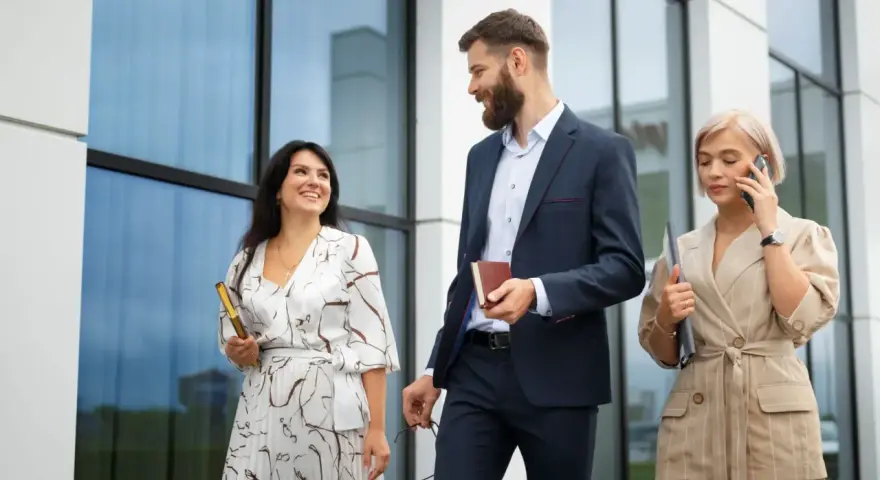 Mujeres con estilo para una conferencia: una con vestido estampado y clutch dorado, otra con traje de lino a rayas y hablando por teléfono.