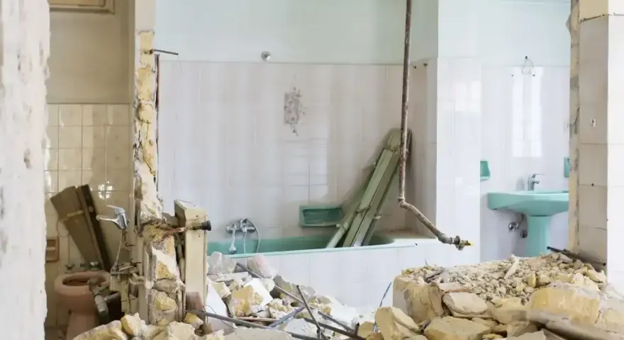 Ruiny łazienki po remoncie. Zniszczone ściany, gruz i wanna. Kara za mieszkanie w nieodebranym domu.