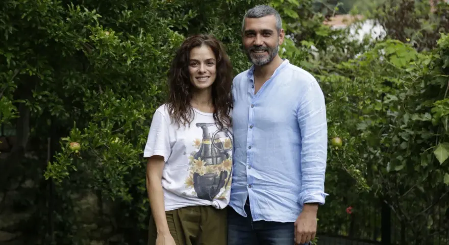 La forza di una donna puntata di oggi: una coppia sorride tra gli alberi. Lei indossa una maglietta con una bomba floreale, lui una camicia azzurra.