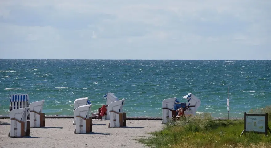 Strandkörbe am Bojendorfer Strand laden zum Entspannen ein. Das Meer glitzert, die Wolken ziehen vorbei.
