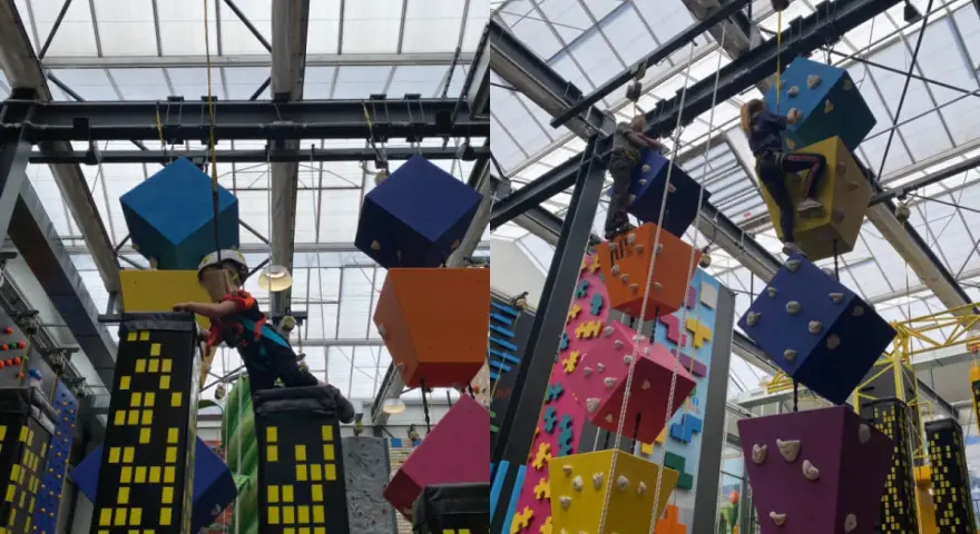 Kinder klettern auf bunte Würfel und Wolkenkratzer in einer Kletterhalle, die an einen Magic Mountain Berlin erinnert.