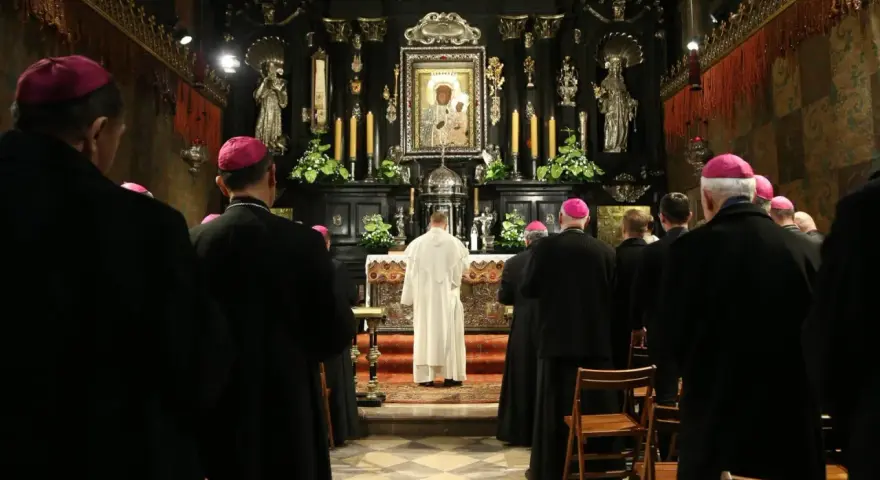 Uroczyste msze święte na Jasnej Górze. Biskupi w czarnych szatach i różowych biretach modlą się przed ołtarzem z cudownym obrazem Matki Bożej.