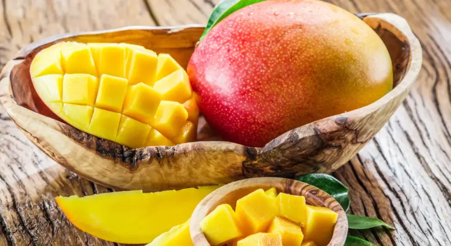 Dojrzałe mango w drewnianej misie, pokrojone w kostkę i plastry. To tropikalne owoce, które zachwycają smakiem i bogactwem witamin. Mango wartości odżywcze są imponujące.