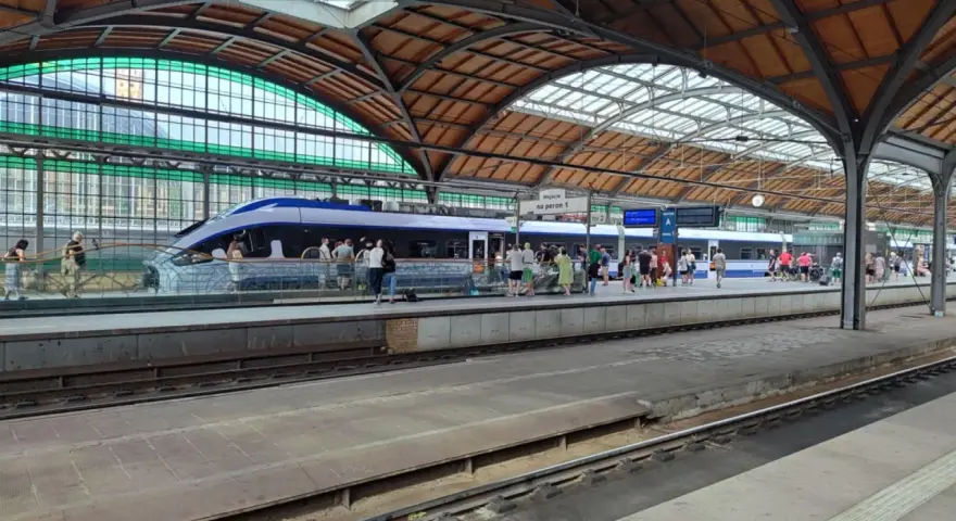 Nowoczesny pociąg kraków wrocław na peronie, pasażerowie czekają na podróż pod zabytkowym zadaszeniem dworca.