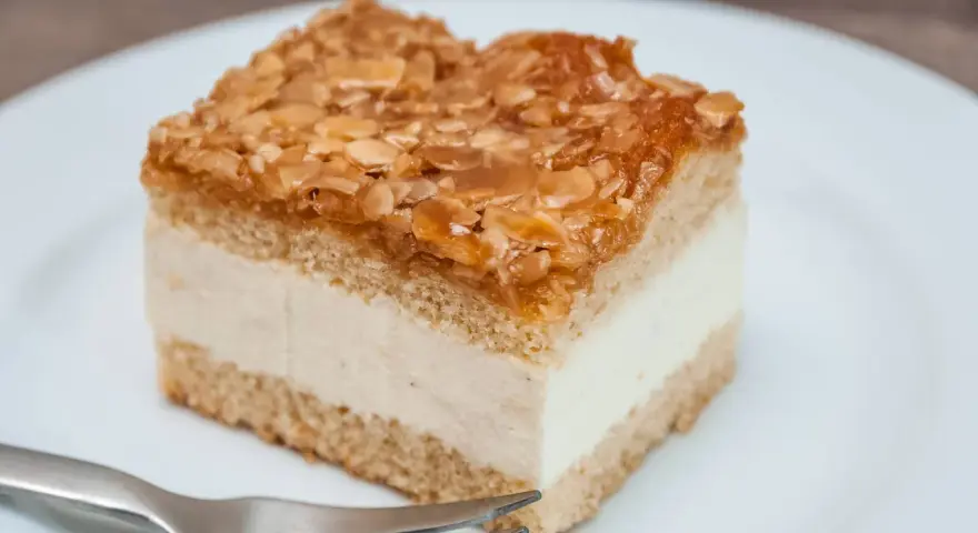 Ein Stück Bienenstich-Kuchen mit cremiger Füllung und karamellisierten Mandeln. Ein leckeres Rezept für den süßen Genuss.