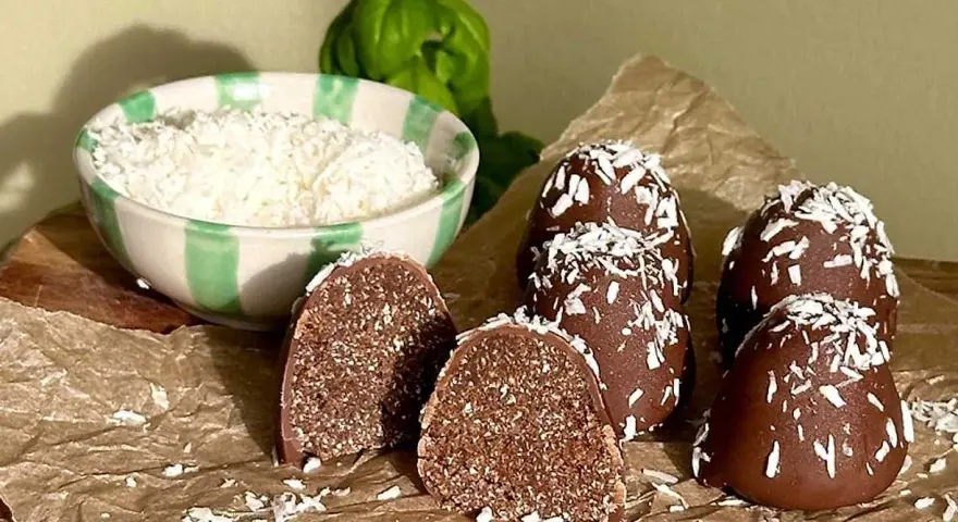 Chokladbollar recept: Mörka, kokosdränkta godsaker med en skål riven kokos i bakgrunden. Perfekt för fikat!