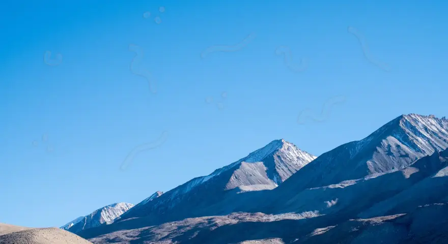 Sullo sfondo di montagne innevate, un cielo azzurro limpido è punteggiato da forme sinchisi scintillante, come piccoli puntini e curve sinuose.