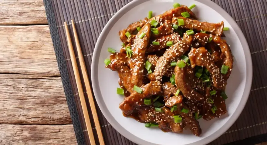 Pyszny kurczak teriyaki z sezamem i szczypiorkiem, gotowy do jedzenia pałeczkami.