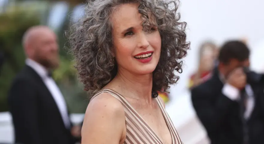 Mujer sonríe con modernos cortes de pelo con canas, luciendo un vestido a rayas.