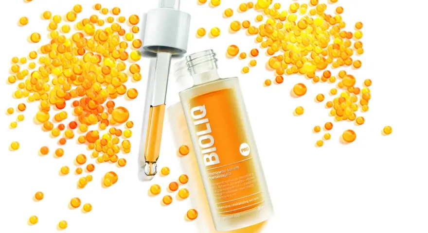 BiolIQ intensywne serum rewitalizujące w buteleczce z pipetą, otoczone kropelkami o pomarańczowym odcieniu.
