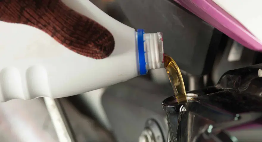 Rękawica nalewa nowy olej do silnika motocykla podczas wymiany oleju.