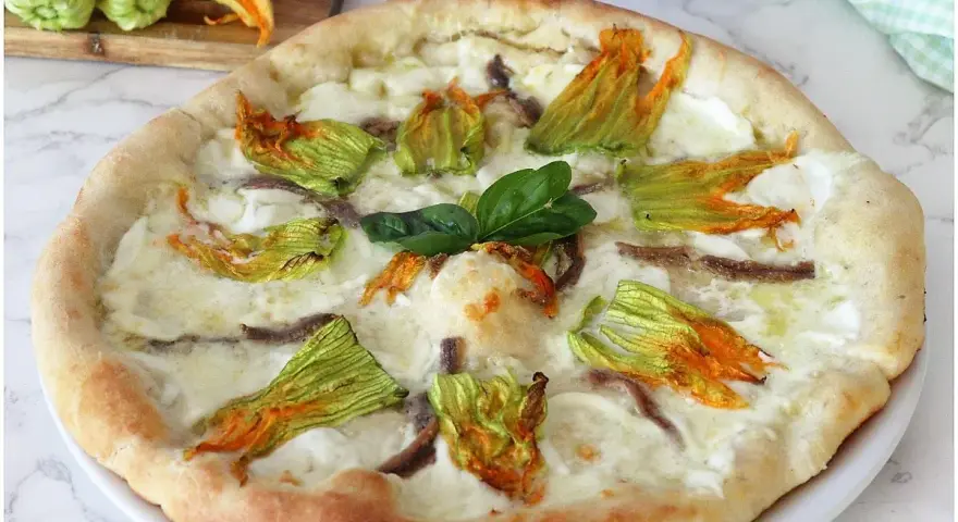 Pizza con fiori di zucca, mozzarella filante e acciughe. Un sapore delicato e profumato, perfetto per l'estate.