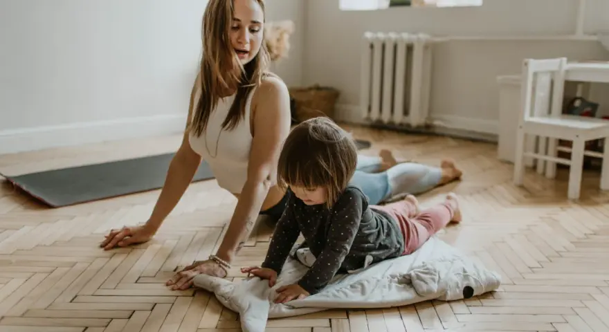 Mama i dziecko ćwiczą jogę. Maluch leży na poduszce w kształcie wieloryba, a mama w pozycji kobry. To świetne ćwiczenia relaksacyjne dla dzieci.