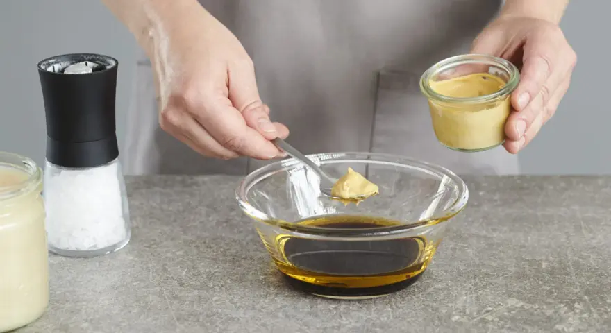 Senf wird zu einer Schüssel mit Öl und Balsamico-Dressing gegeben.