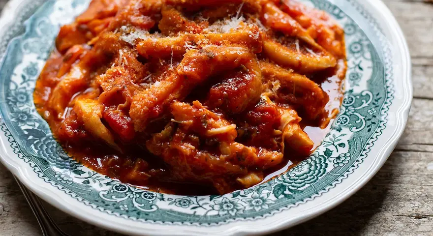 Un piatto fumante di trippa alla romana, ricca e saporita, servita su un piatto decorato.