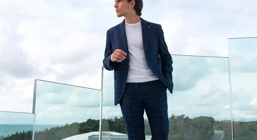 Uomo con tailleur blu a quadri, maglione bianco. Perfetto per capire con che scarpe abbinare.