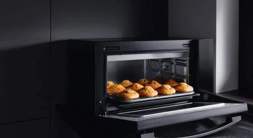 Horno de leña empotrado con bandeja de muffins recién horneados.