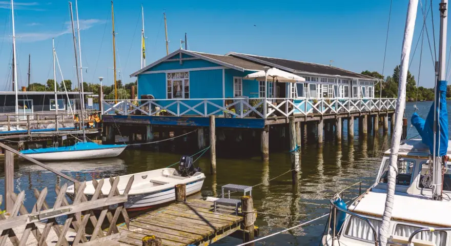 Blaues Haus am Wasser mit Booten, ein idyllisches Motiv für Schlei Ausflugsziele.