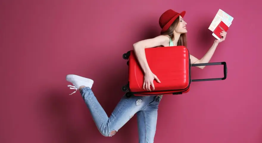 Kobieta z walizką i paszportem zastanawia się, ile kosztuje dodatkowy bagaż w Ryanair.