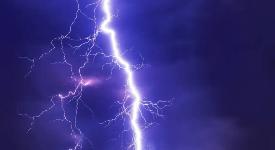Potężne wyładowanie atmosferyczne rozświetla nocne niebo. Burza może oznaczać problemy, ale pamiętaj o możliwości uzyskania odszkodowanie za brak prądu.
