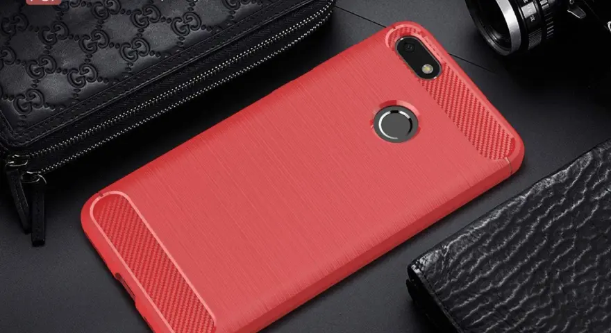 Czerwone etui na telefon Huawei Y6 Pro (2017) z karbonowymi wstawkami, obok czarnego portfela i aparatu.
