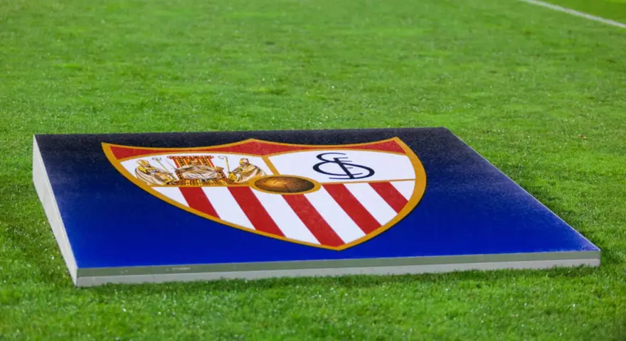 Herb Sevilla FC na tle murawy. Gotowość do kolejnych rozgrywek.