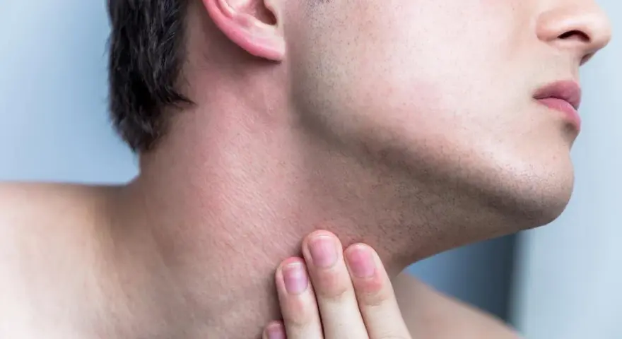 Hombre tocando su cuello con irritación y pequeños granos después de afeitarse.