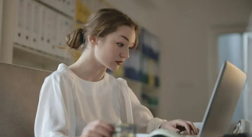 Młoda kobieta uczy się, jak zostać księgowym bez studiów, korzystając z laptopa i karty.