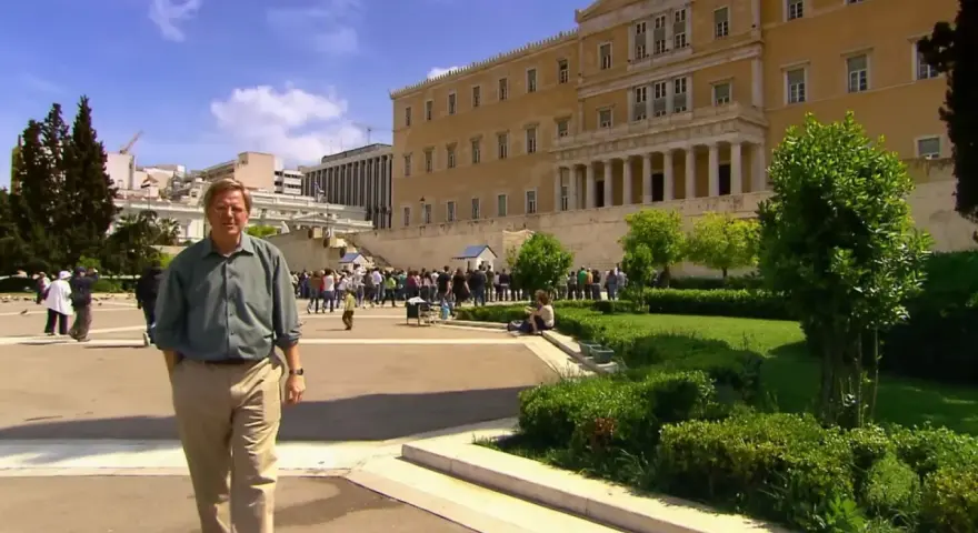 Rick Steves explores Athens, standing before the Hellenic Parliament building with a crowd gathered for the changing of the guard.