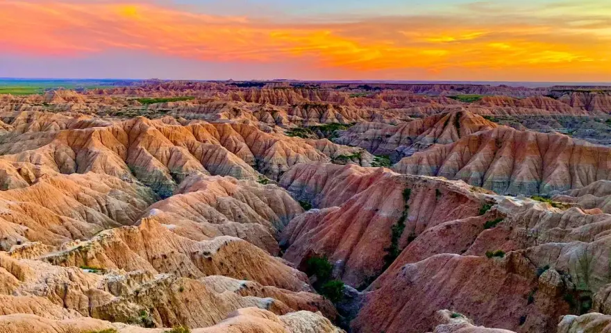 Un paisaje desértico con formaciones rocosas erosionadas, **las carcavas**, bajo un cielo anaranjado y azul al atardecer.