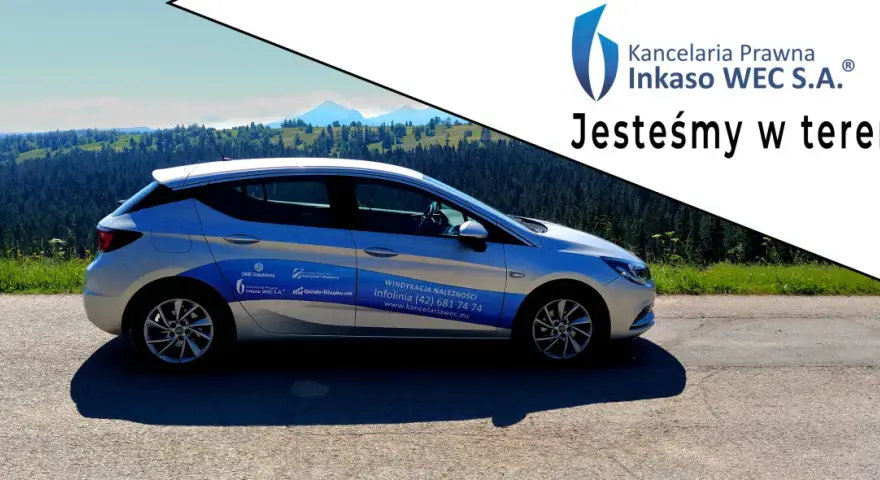 Srebrny samochód Kancelarii Prawnej Inkaso WEC S.A. z napisem "Jesteśmy w terenie!" na tle górskiego krajobrazu.