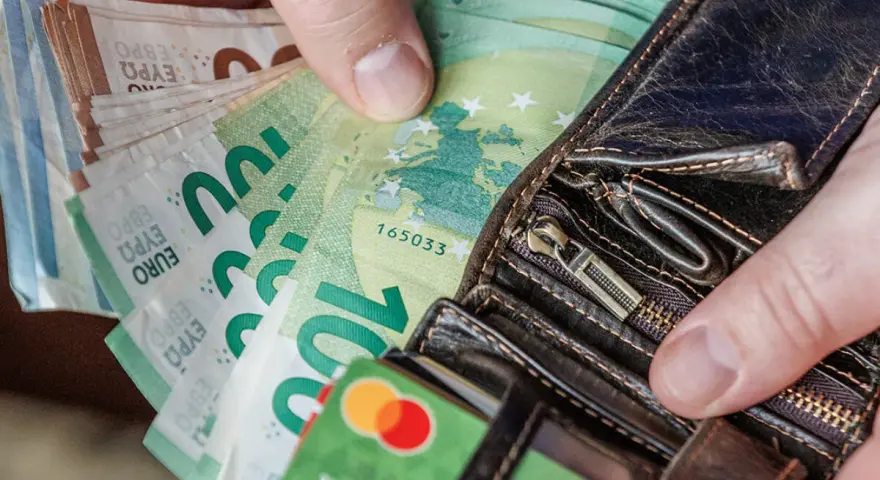 Ręce trzymające euro banknoty i karty płatnicze. Odpowiedź na pytanie: jaka waluta na Litwie? Euro.