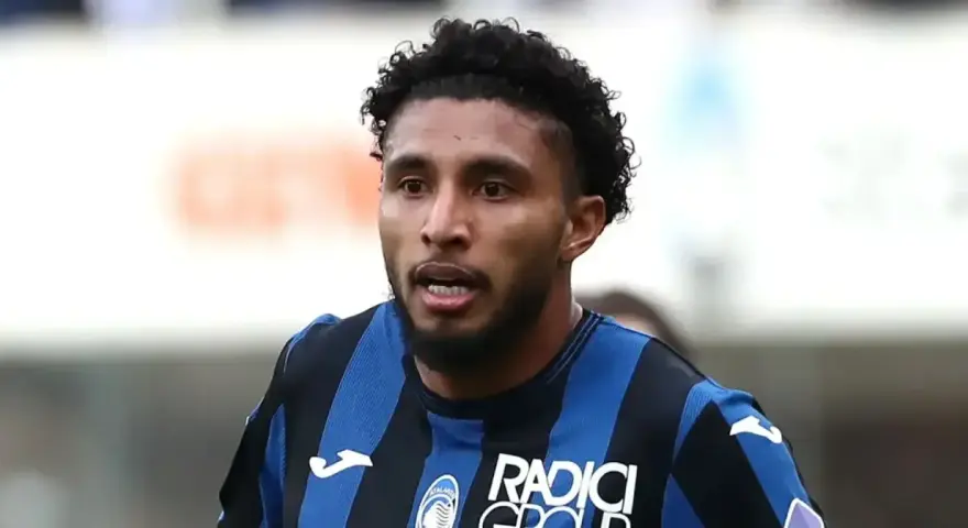 Primer plano de Éderson dos Santos, jugador de fútbol con pelo rizado y barba, vistiendo una camiseta a rayas azules y negras.