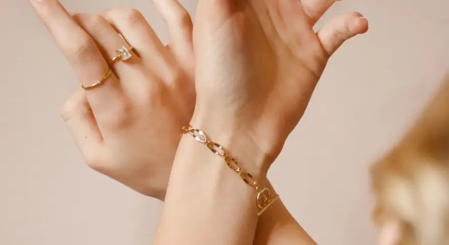 Mani adornate con anelli e un bracciale in metallo che sembra oro, un tocco di eleganza discreta.