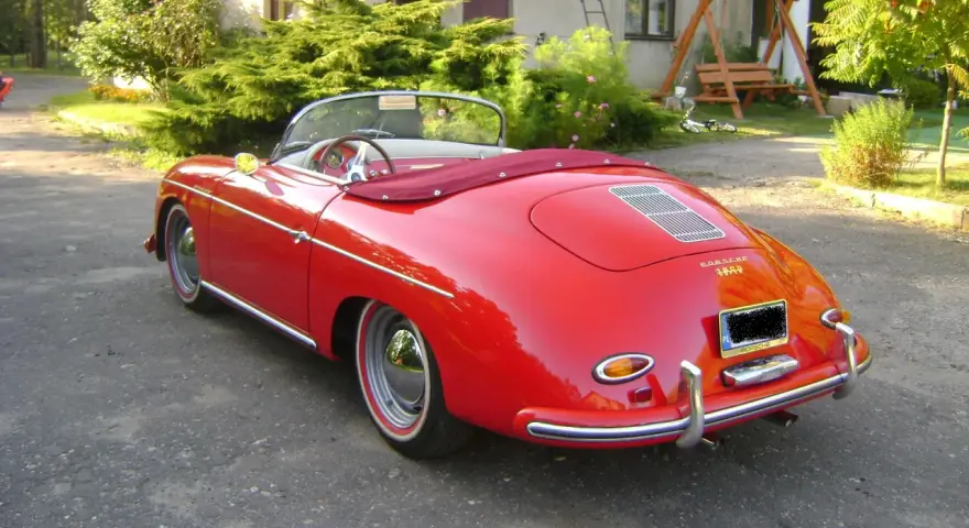 Czerwony kabriolet Porsche 356 z lat 50. stoi na podjeździe, gotowy na letnią przejażdżkę.
