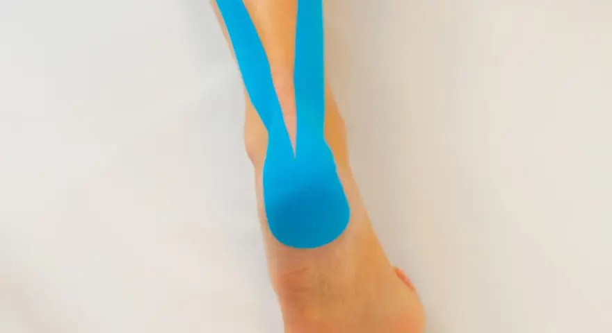 Blaues Kinesio-Tape stützt den Fuß und Unterschenkel, um Schmerzen zu lindern.