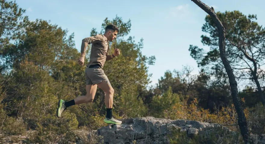 Mężczyzna w letniej odzieży sportowej pokonuje kamienisty teren, doskonaląc swój trening biegowy metodą Skarzyńskiego.