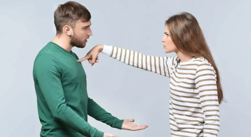Une femme pointe du doigt un homme, exprimant son mécontentement. Ce geste symbolise les choses à ne pas accepter en couple, comme le manque de respect ou la communication agressive.