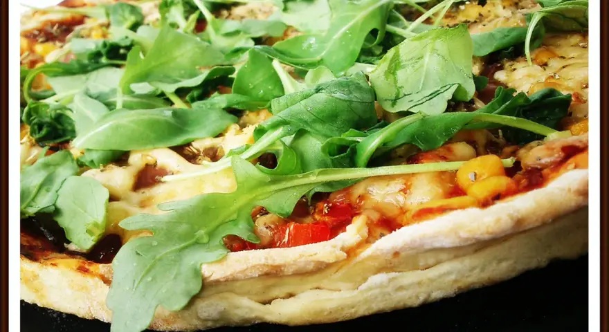 Pyszna pizza z rukolą, pomidorami i serem, pachnąca ziołami. Idealna na szybki obiad.