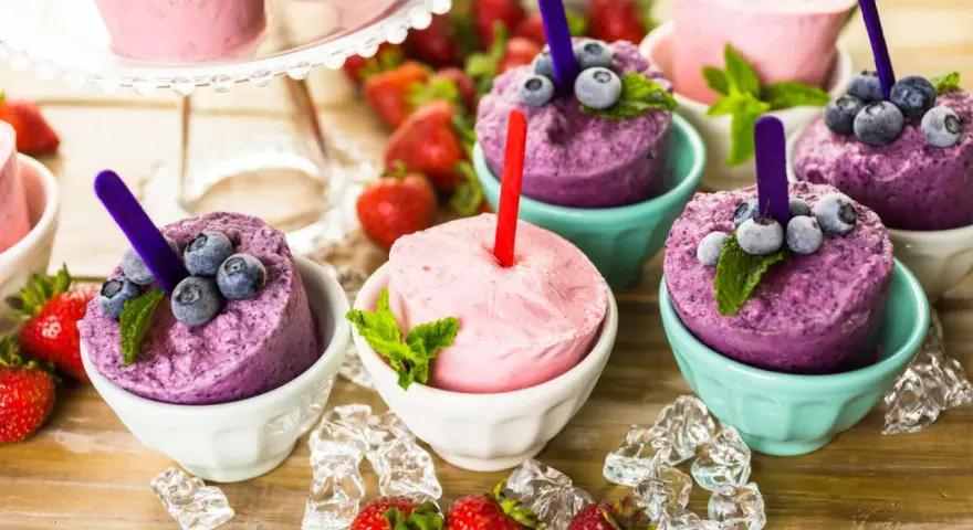 Erfrischendes Eis in Schalen, perfekt zum **Crème double selber machen**. Blaubeeren und Erdbeeren garnieren die bunten Leckereien.