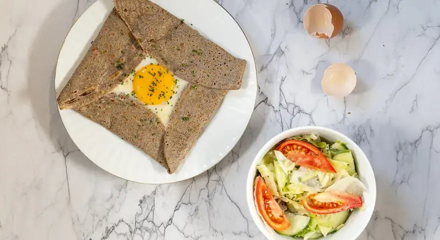 Galette de sarrasin garnie d'un œuf au plat, parfaite pour savoir que mettre dans une galette bretonne. Accompagnée d'une salade fraîche.