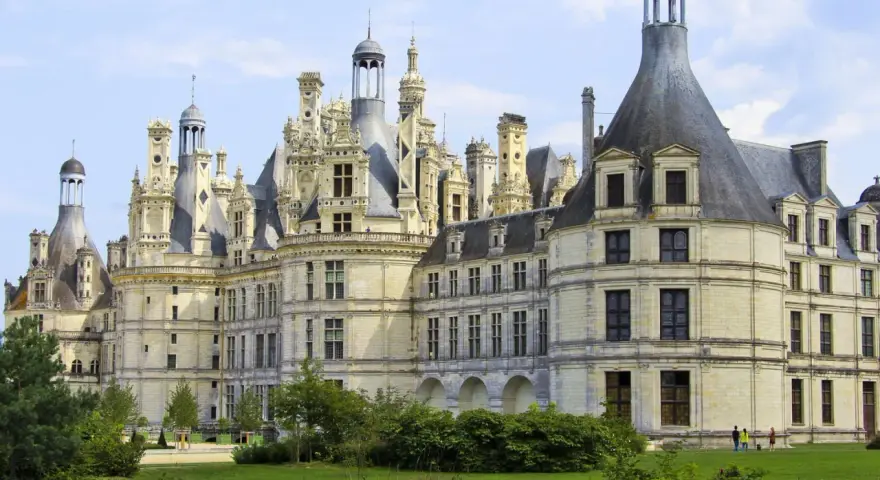 Le château de Chambord, chef-d'œuvre de la Renaissance, se dresse majestueusement sous un ciel bleu. Ses tours et cheminées sculptées rappellent une époque de splendeur.