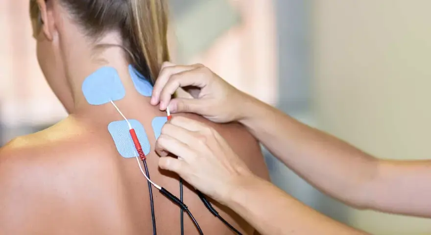 Elektrody na karku i plecach pacjentki, przygotowywane do zabiegu prądami na kręgosłup.