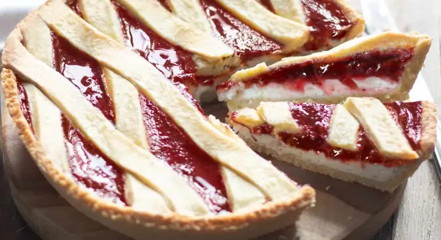 Una deliziosa crostata ricotta e marmellata, con una fetta tagliata per mostrare il ripieno cremoso e la crosta dorata.