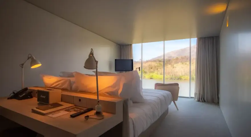 Un angolo studio in camera da letto con vista sul lago. Due lampade illuminano la scrivania con telefono e altoparlante.