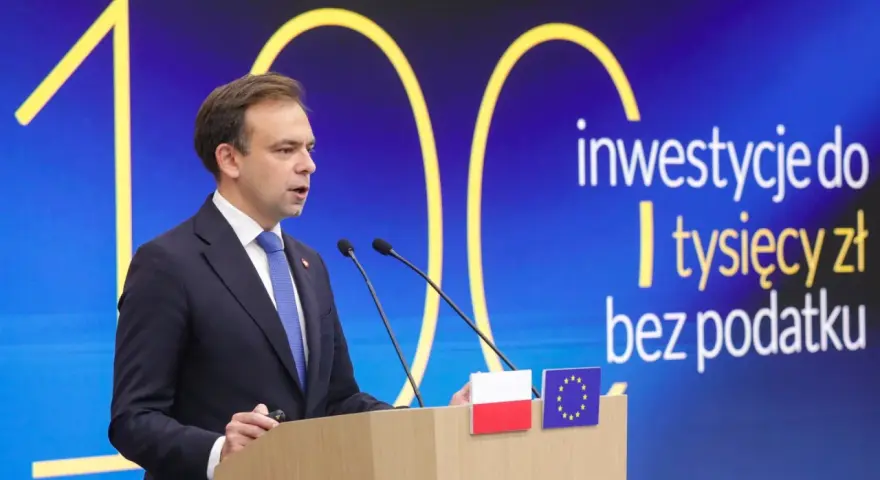 Mężczyzna w garniturze przemawia na tle napisu "inwestycje do tysięcy zł bez podatku". Czy od obligacji płaci się podatek?